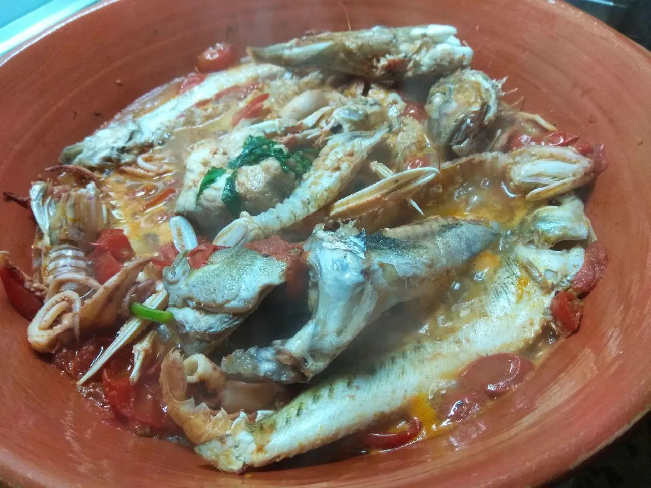 Brodetto di pesce fumante nel tegame di coccio, con pomodoro e crostacei.