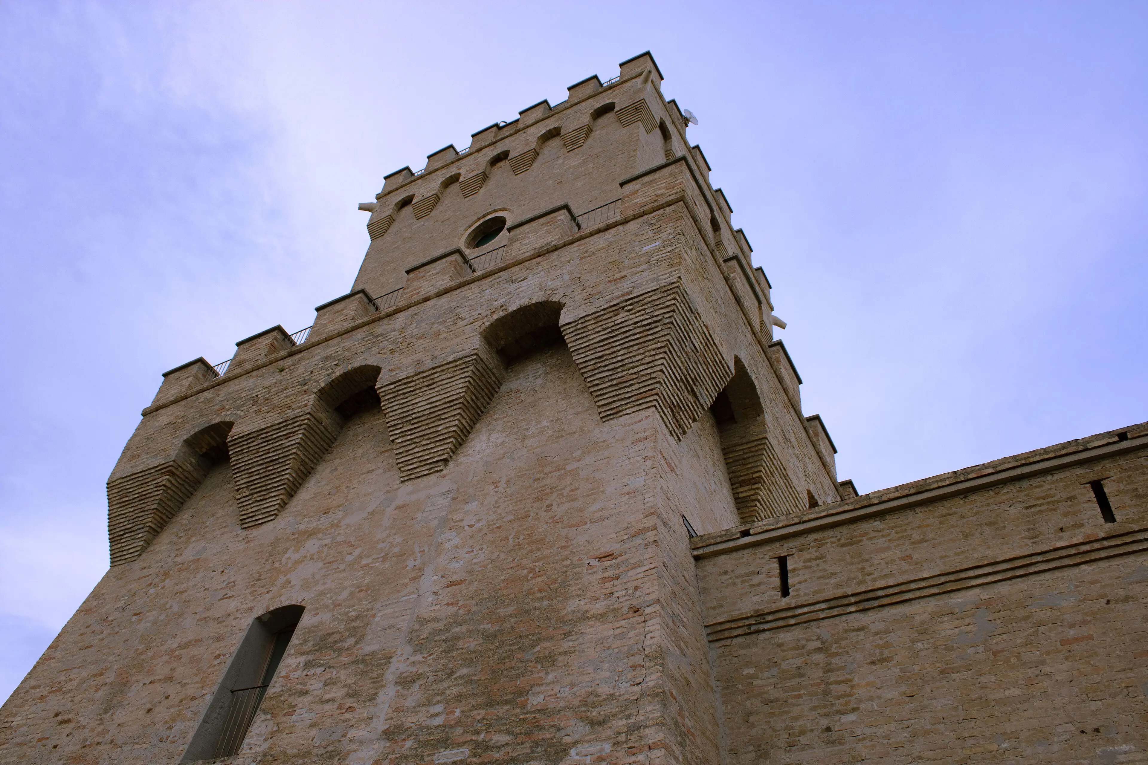 I mattoni caldi della Torre del Cerrano visti dal basso contro il cielo azzurro.